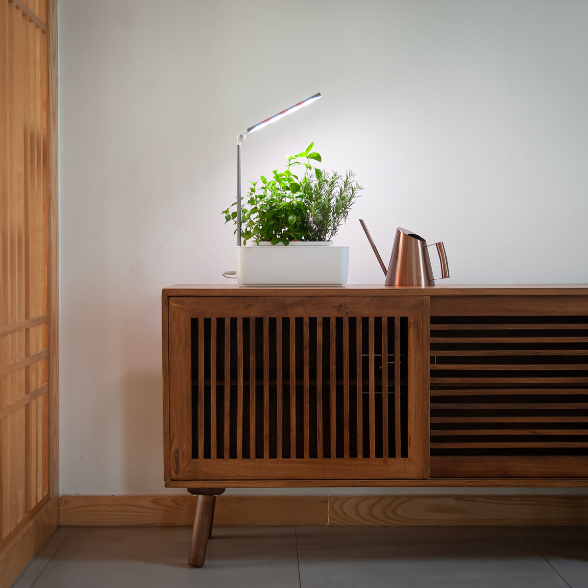 HydroGarden Classic with tilted lamp head growing herbs on a wooden cabinet.