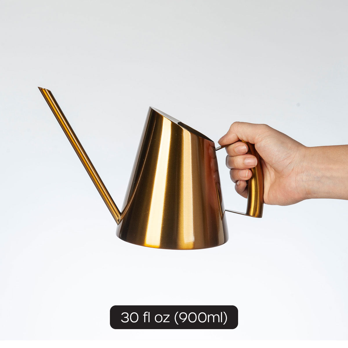female hand model holding large gold mini watering can showing 30 fl oz volume.